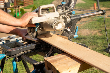 cutting a wooden plank with a table saw (bench saw) to make a diy table