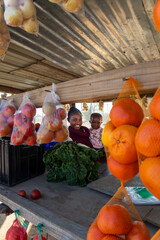 Happy African street vendor hawker village , woman with braided hair holding her child , shack with...