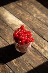 Fresh red currant berries in a glass on a wooden background