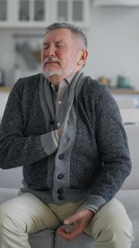 Heart attack of aged male person, portrait of old man feeling sharp pain in upper quadrant, vertical video. Sick senior man grabbing chest, screaming loudly, dangerous health conditions, healthcare