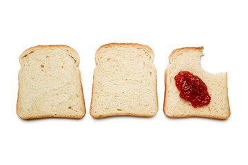 Slices of white bread with strawberry jam and bitten on white background, top view.