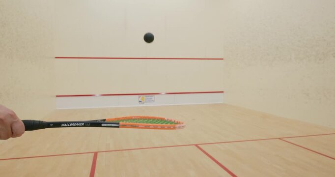 Unrecognizable player bouncing a squash ball with their racket inside the court. Close up, wide angle shot, real time