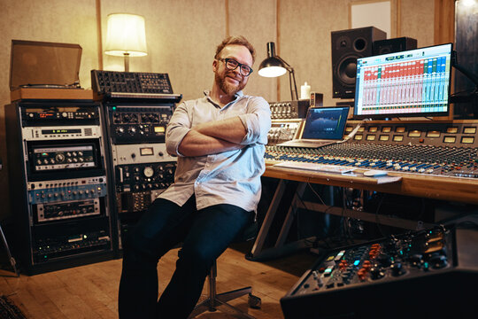 Smiling music producer sitting in his recording studio