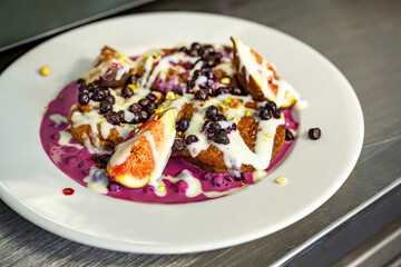 Dessert with fig, blueberry and creamy sauce on plate, closeup.