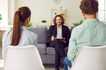 Obraz premium Young couple sitting back on chairs and listening to psychologist advice trying to find problems and solution at counselor's office. Family therapy, relationship and mental health concept.