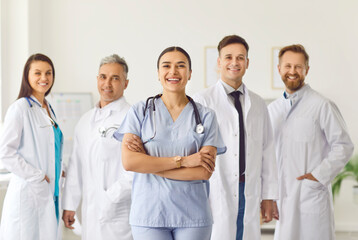 Portrait of a happy confident successful team of young doctors in uniform looking cheerful at camera and smiling while standing in hospital or clinic. Medical staff and health care concept.