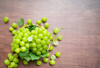 Fresh Green grape in Bamboo basket on wooden table in garden, Shine Muscat Grape with leaves with blank space in wooden background.