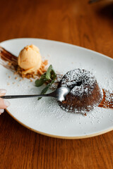 delicious dessert with creamy frosting, chocolate, fresh nuts, and fragrant herbs on a beautiful white plate in a cozy nice restaurant