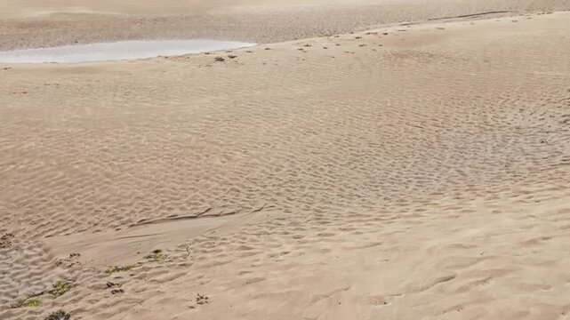 Vertical pan from beach to sky of view from Daymer Bay towards Padstow at low tide