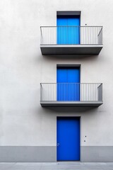 Obraz premium A minimalist grey residential complex with simple, angular architecture. There is a single, vibrant blue door, creating a focal point in the monochromatic setting. 