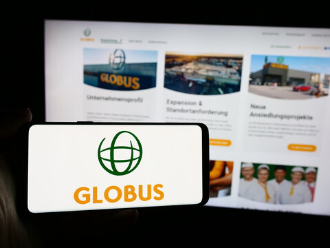 Stuttgart, Germany - 07-31-2024: Person holding mobile phone with logo of German retail company Globus Holding GmbH Co. KG in front of business web page. Focus on phone display.