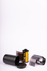 Old film rolls aligned in the center against a white background. Vertical format with ample white space, highlighting vintage cinema.