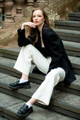 Young woman with long hair black jacket and white trousers street style