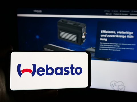 Stuttgart, Germany - 08-05-2024: Person holding mobile phone with logo of German automotive company Webasto SE in front of business web page. Focus on phone display.