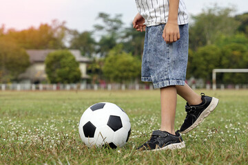Asian boy kicking ball in soccer field. Concept. outdoor activity, sport, playground, leisure activity. Soft and selective focus.