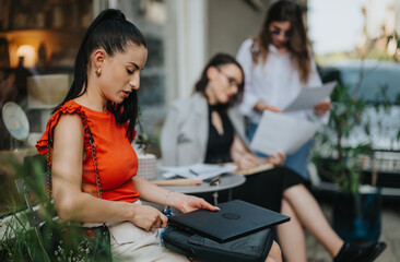 Businesswomen having a meeting outdoors, discussing and reviewing documents. Professional women collaborating in an informal setting.