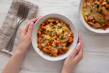 Female hands hold a bowl with homemade One-Pot Cheesy Taco Pasta, top view. Flat lay, overhead, from above.