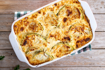 Casserole with cheese and gratin zucchini on wooden table. Top view