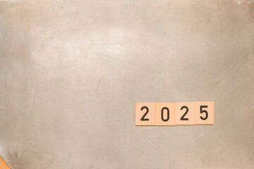 2025 numbers on a metal or aluminum background. Wooden blocks. Soft light of the Transcendent Pink color. Concept 2025 New Year background. Copy space. 