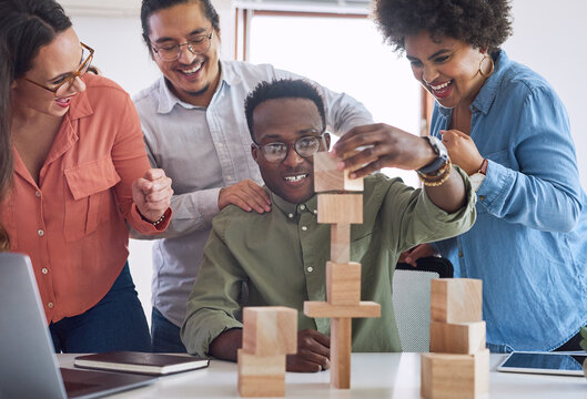 Office, employees and happy on teamwork with building blocks for problem solving, solution and educational. Diversity, people and excited for game success, cheering and creativity as graphic designer