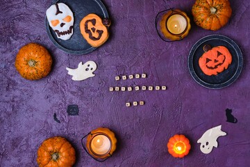 Halloween theme cookies with colorful icing on purple concrete background. Children's party. Happy Halloween concept.