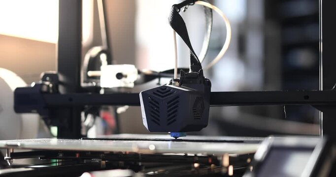 Close-up of a 3D printer head working in the rays of the setting sun. 3D printing technology in dynamic lighting, perfect for illustrating modern manufacturing.