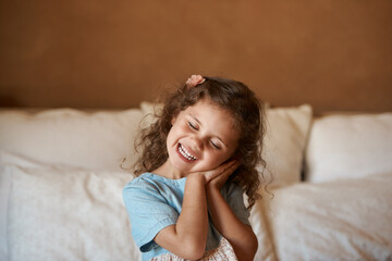 Fototapeta premium Girl, child and eyes closed with play in bedroom with sign for sleep, comic game and smile in family house. Kid, happy and excited on bed for funny memory in morning at apartment in New Zealand
