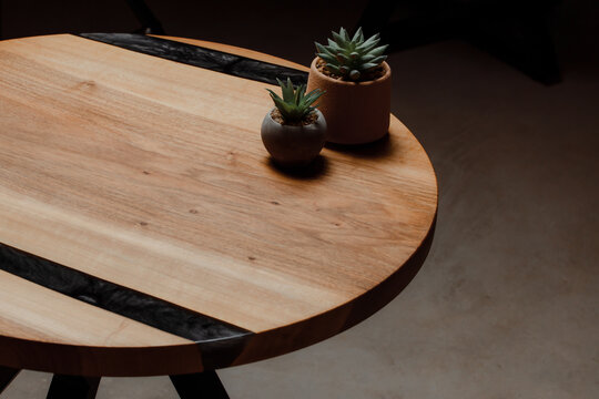 Expensive vintage furniture. The table is covered with epoxy resin and varnished. Luxury quality wood processing. Wooden table on a dark background. Home desktop cacti in concrete pots.