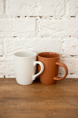 brown and white cups stand on a wooden table near a white wall