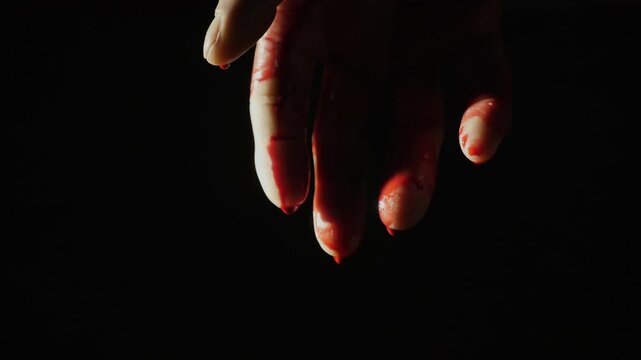 On the human hand, natural blood flows down against a dark background. Close-up