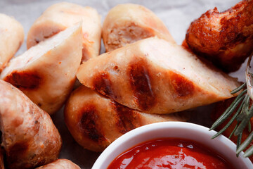Original serving of meat dishes. Crispy fried chicken wings and thighs. Breaded cheese balls and grilled sausages with rosemary and ketchup. Food for outdoor catering.