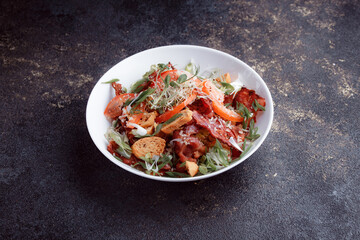 Salad panzanella of tomatoes and paper with fresh greens. Fresh vegetable mix at dark table. Top view, Copy space.