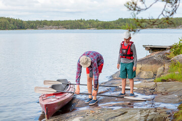 Father and son are preparing for kayaking by the sea, canoeing, boating in the Baltic sea during family summer vacations in Finland