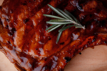 Grilled piece of meat. Crispy chicken wings. The texture of the meat is very close up. Seasoning in the form of ketchup and sprigs of rosemary.