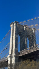 Fototapeta premium Massiver Pfeiler der Brooklyn Bridge mit Stahlseilen und blauem Hintergrund