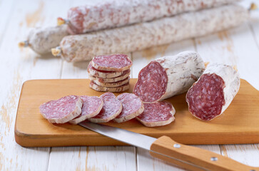 Sliced salami sausage, knife and cutting board, selective focus.