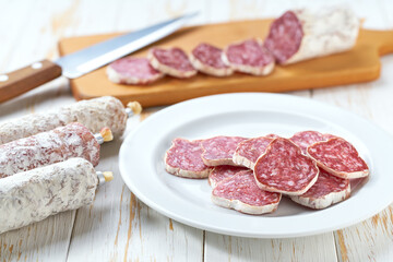 Spanish salami fuet sausage or dry sausage cut in slices on a white ceramic plate, on a kitchen table.