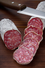 Slices of delicious spanish sausage fuet on a wooden table, selective focus.