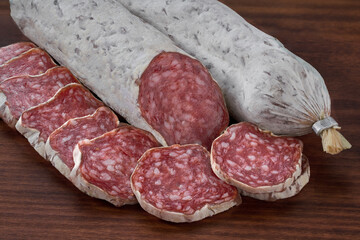 Slices of delicious spanish sausage fuet on a wooden table, selective focus.
