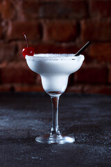 Alcoholic cocktail white prince. Light cocktail drink with a cherry on a dark blue textured background.