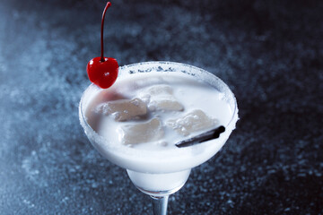 Alcoholic cocktail white prince. Light cocktail drink with a cherry on a dark blue textured background.