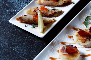 Set of pancakes with red salmon caviar. Beautiful serving of the dish on a textured dark blue background. Restaurant dessert menu.