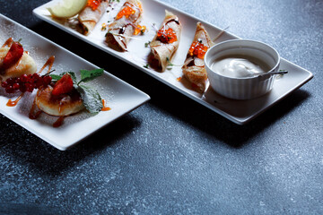 Set of pancakes with red salmon caviar. Beautiful serving of the dish on a textured dark blue background. Restaurant dessert menu.