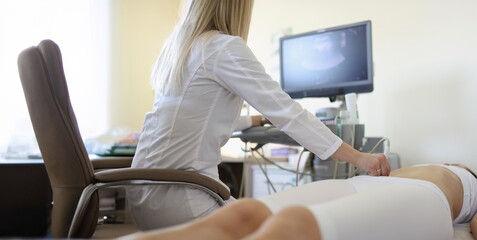 Woman doctor makes an ultrasound of the abdomen of a woman, rear view. Clinical consultation and diagnosis of diseases