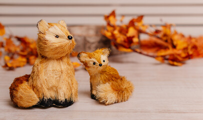 Handmade fox figurines placed in a rustic setting with autumn leaves, perfect for cozy and seasonal designs.