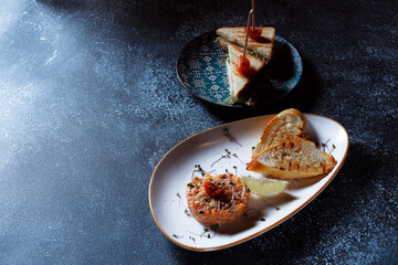 Vegetable salad and fried crisps. A dish served in a restaurant. White plate on a dark blue background.