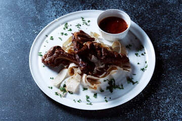 A large piece of spicy grilled meat. Ribs fried to a crisp with spices and herbs. Restaurant serving dishes with sauce and micro-herbs.