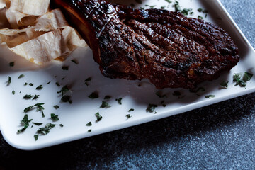 A large piece of spicy grilled meat. Bone-fried meat with spices. Restaurant serving dishes with sauce and micro-herbs.