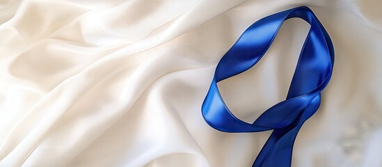 A deep blue ribbon curl on white fabric with copy space Colorectal cancer awareness colon cancer in older adults and World Diabetes Day as well as child abuse prevention Healthcare and insurance them
