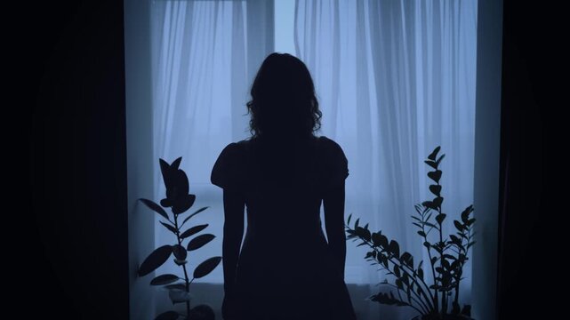 unrecognizable black dark silhouette of woman standing looking at window, mood depression sadness loneliness emotion. Mystery Adult Girl back rear view. wind blows curtains fly waving white fabric 4k